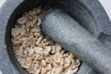 Maak de cashewnoten fijn in een vijzel